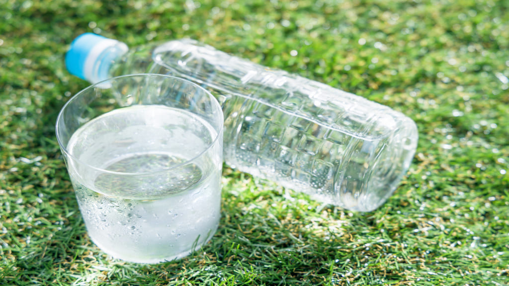 ペットボトルの横に置かれたコップに入った水
