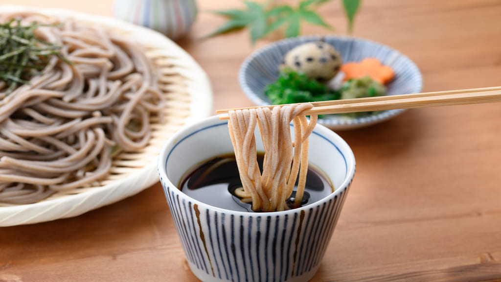 ざるそばをめんつゆに浸ける様子