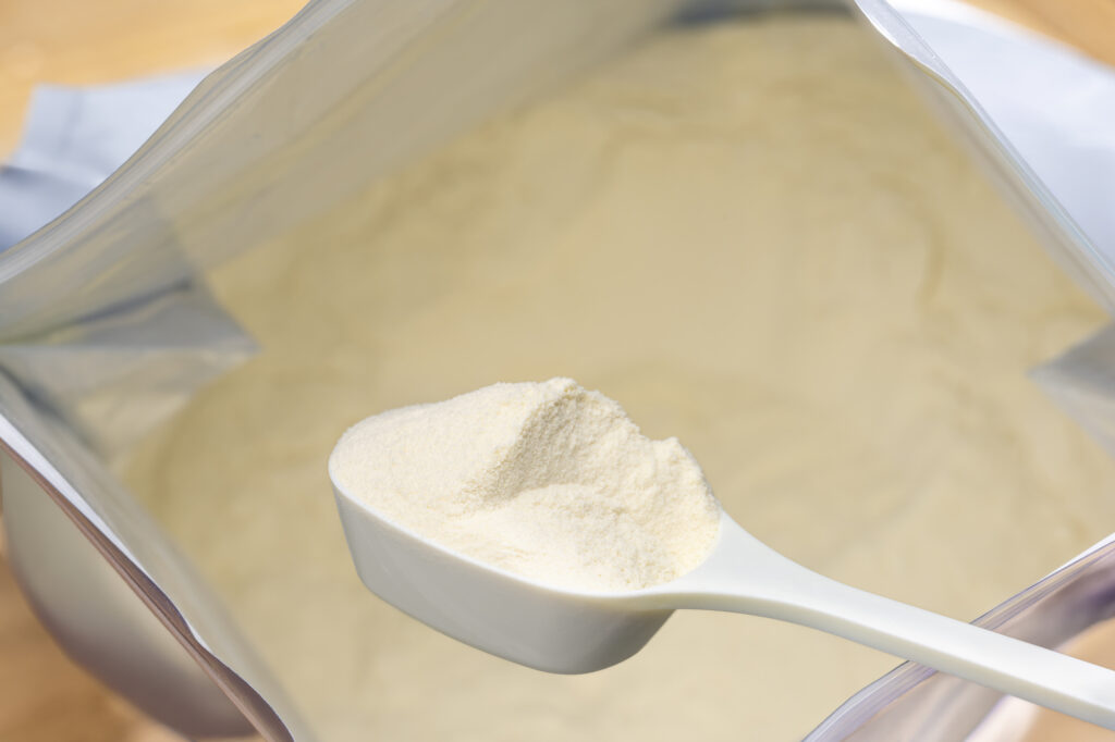 プロテインの大袋とスプーンに乗ったプロテインの粉